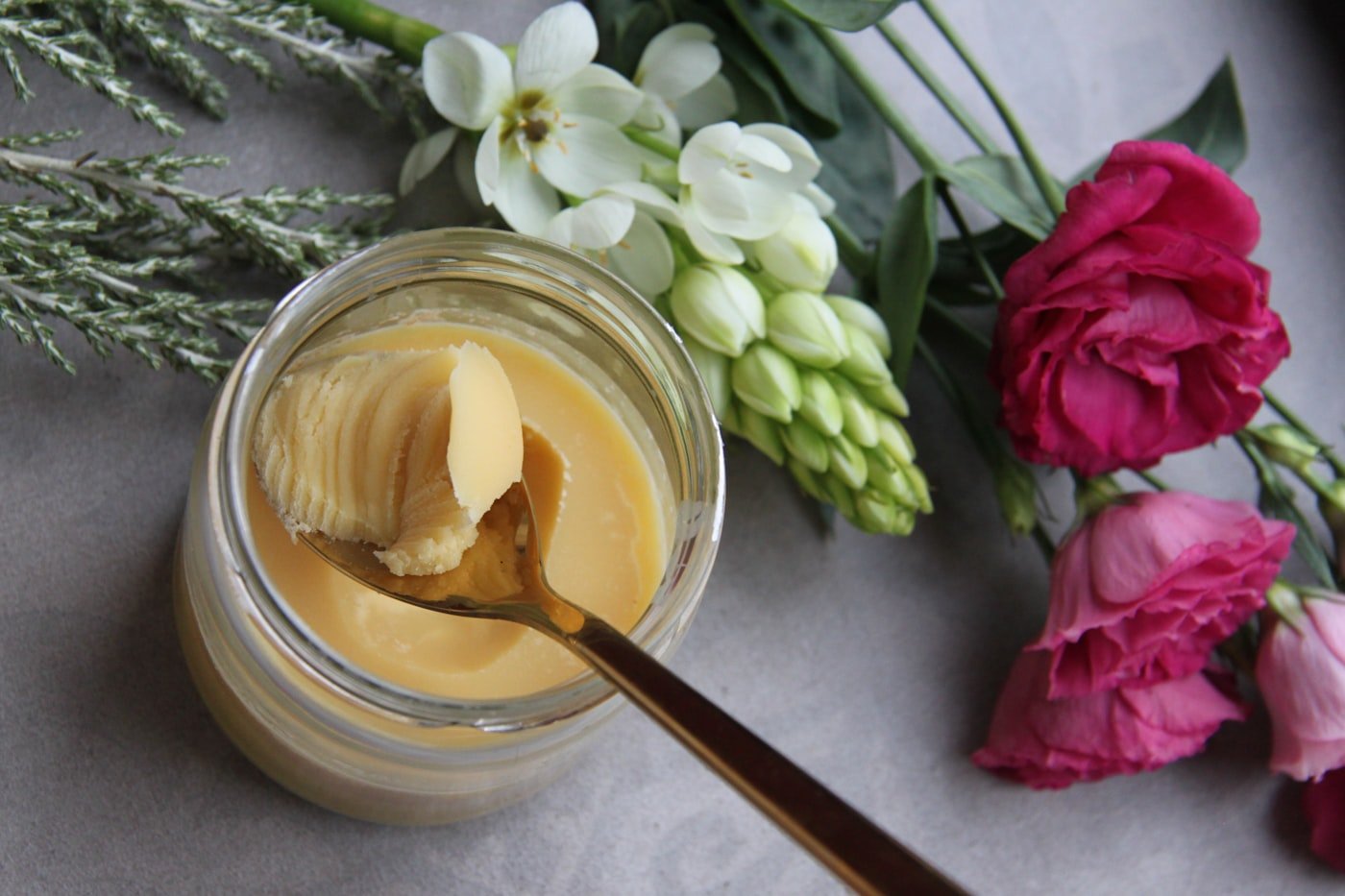 Jar of natural body butter with a wooden spoon